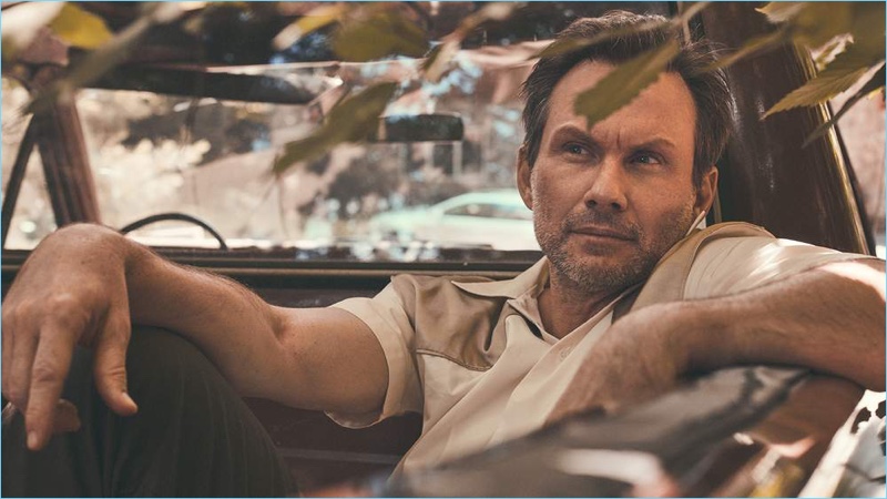 Relaxing, Christian Slater wears a Maison Margiela shirt and Maison Kitsuné trousers.