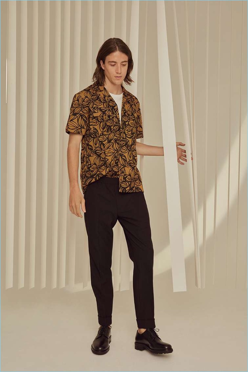 Lucian Clifforth sports a Club Monaco flower print shirt, pocket tee, trousers, and W&H officer shoes.