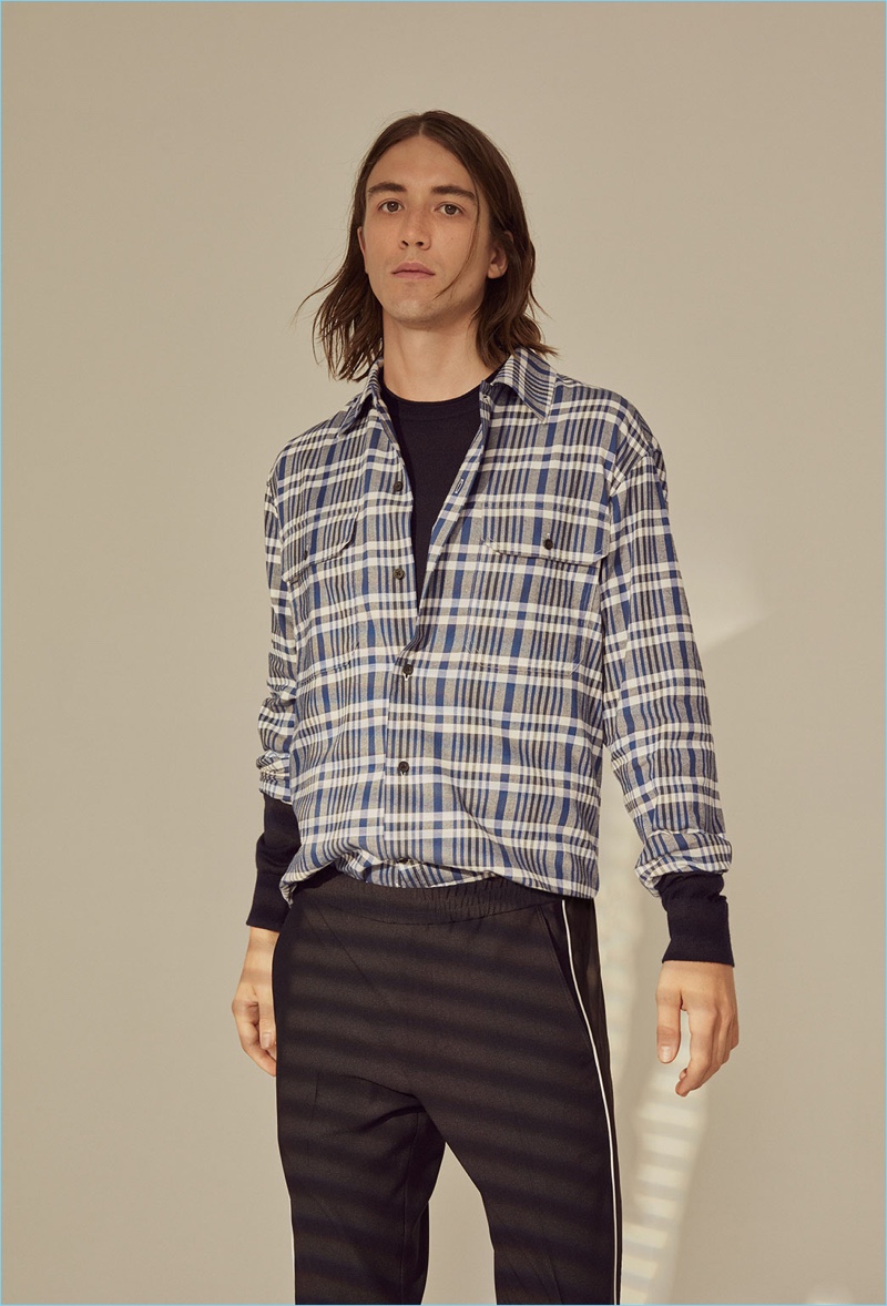 Model Lucian Clifforth wears a Club Monaco pullover, plaid shirt, and pants.