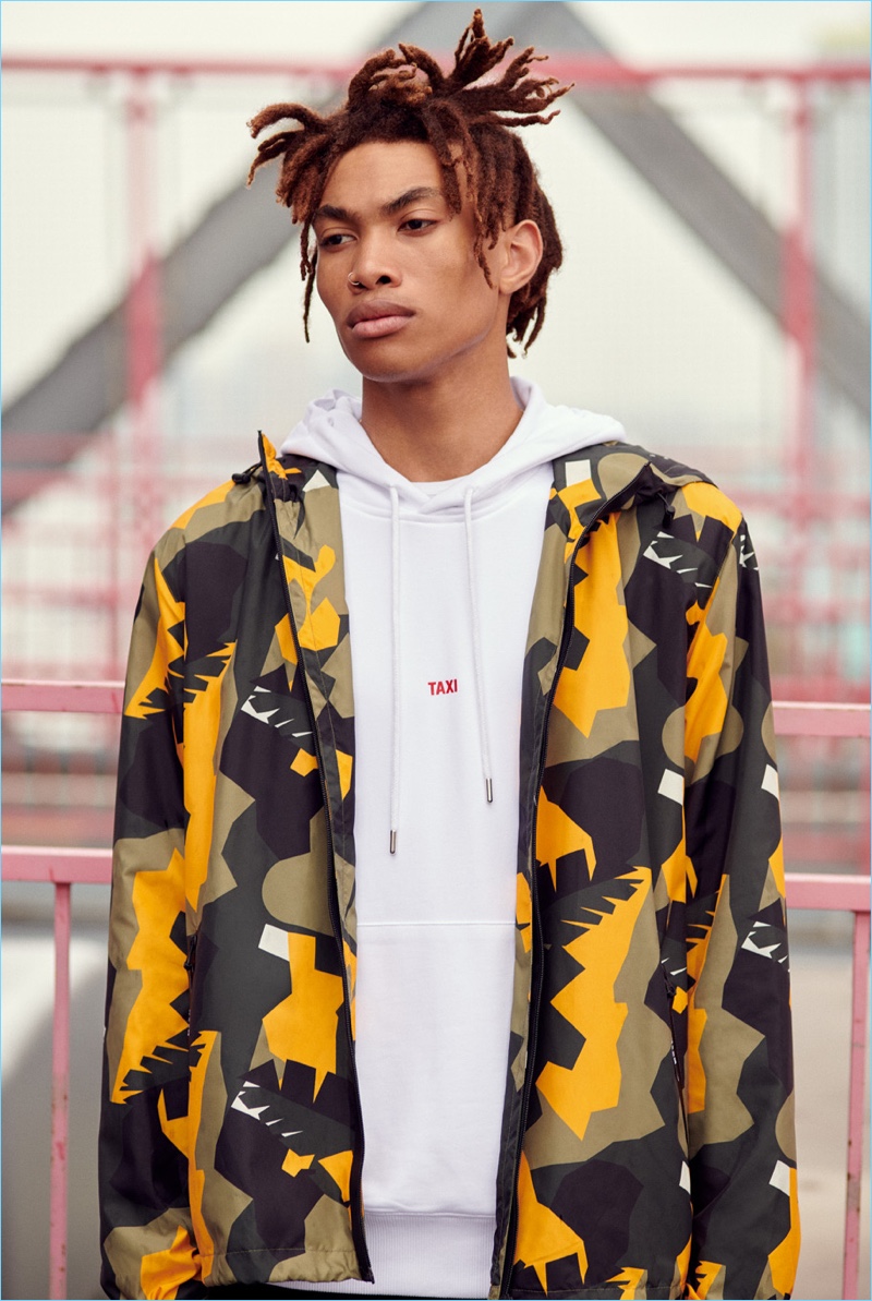 Seth Hill models a Helmut Lang hoodie and pants with a MSGM camouflage print windbreaker. 