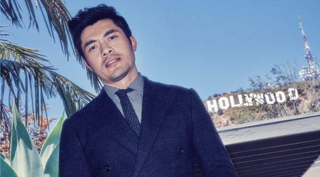 Henry Golding wears a sharp suit, shirt, and tie by Ralph Lauren.