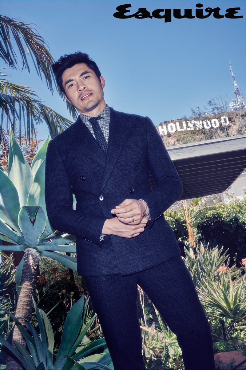 Henry Golding wears a sharp suit, shirt, and tie by Ralph Lauren.