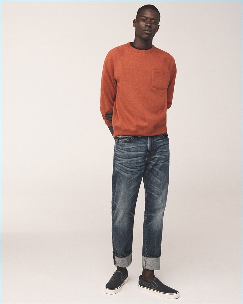 Alpha Dia wears a J.Crew sweatshirt, striped t-shirt, and 1040 athletic fit jeans with Vans sneakers.