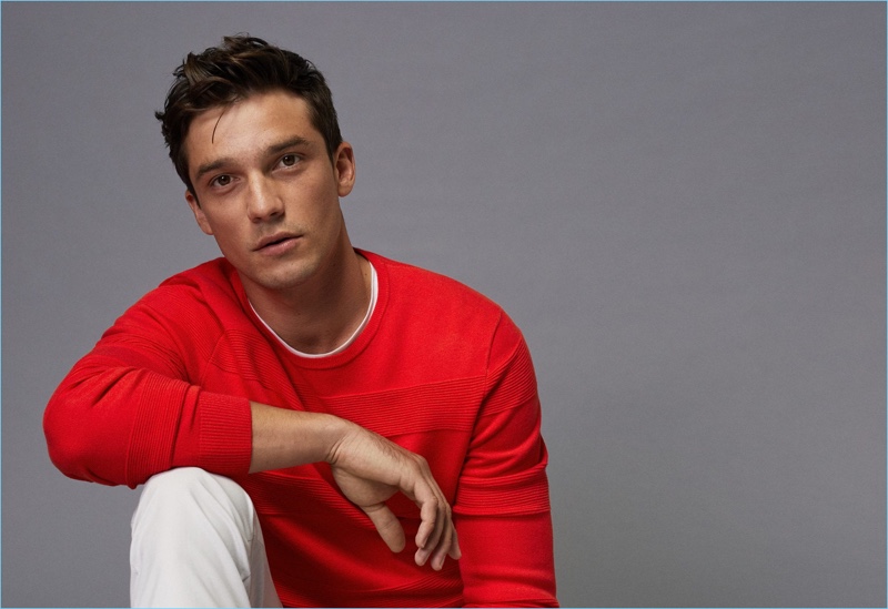 Model Alexis Petit sports a red sweater with white pants from Mango Man.