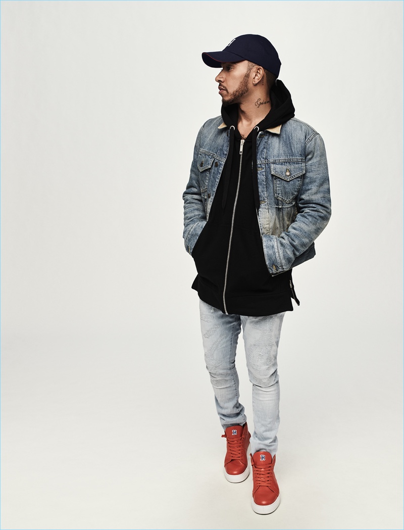 Doubling down on denim, Lewis Hamilton dons a denim jacket, hoodie, jeans, cap, and sneakers from his Tommy Hilfiger collection.