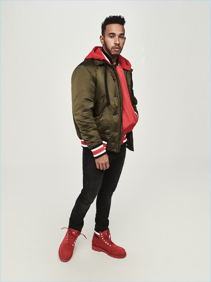 Donning a bomber jacket, Lewis Hamilton also wears a souvenir jacket, jeans, and hiking boots from his Tommy Hilfiger collection.