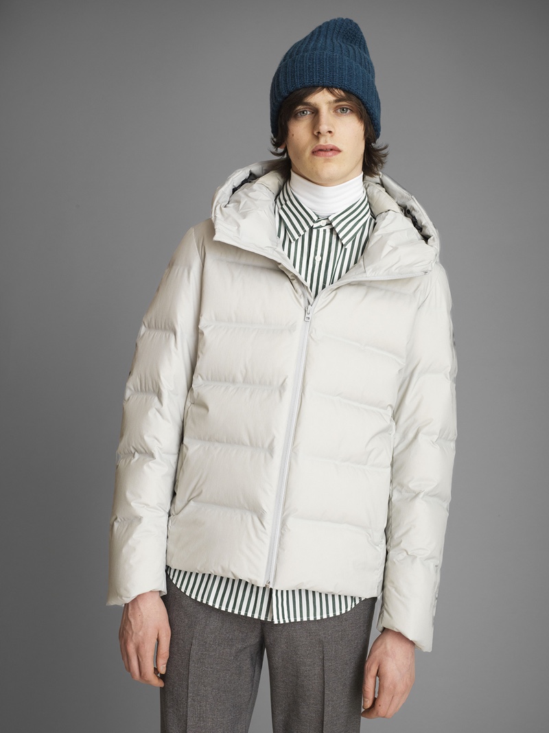 Alistair Waterfield sports a down jacket with a turtleneck, striped shirt, and pleated trousers by UNIQLO.