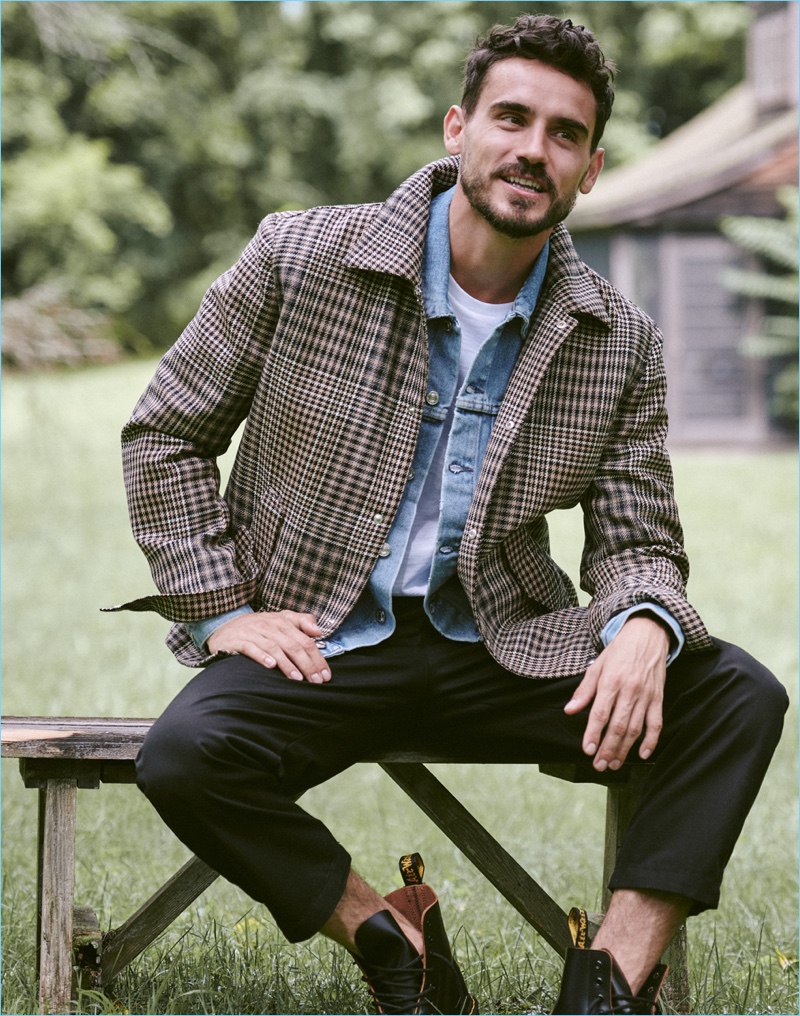 Model Arthur Kulkov sports an AMI jacket, Our Legacy denim jacket, Vince tee, Helmut Lang cropped pants, and Dr Martens boots.