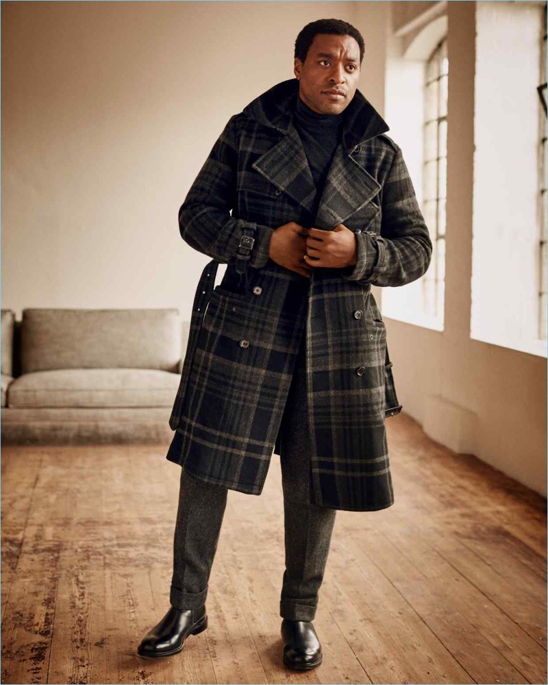 Actor Chiwetel Ejiofor sports a Ralph Lauren Purple Label trench coat, turtleneck, and trousers with Church's boots.