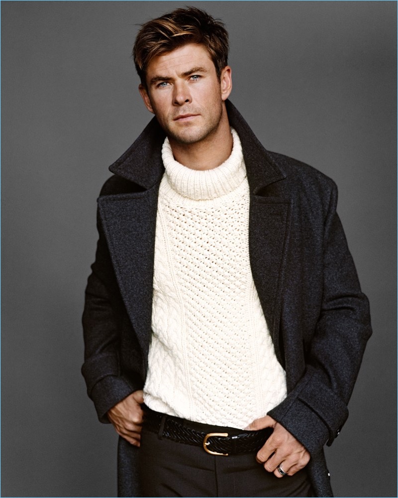 Appearing in a new photo shoot, Chris Hemsworth wears a BOSS coat, and Michael Kors sweater. He also dons a Tom Ford leather belt and pants.