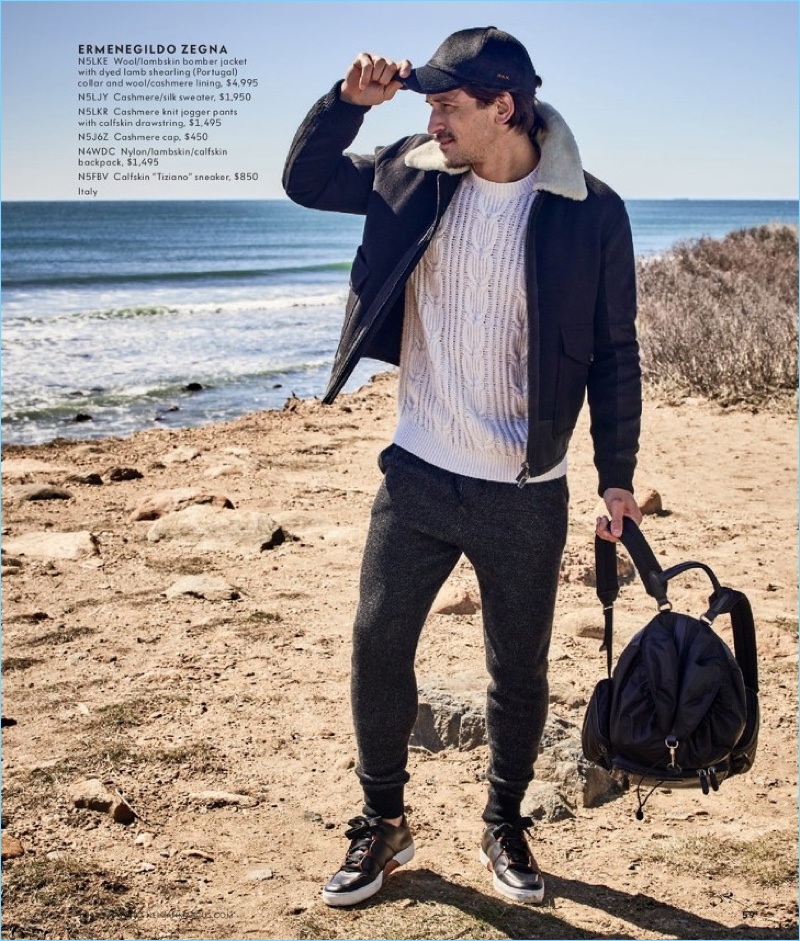 A cool vision, Jarrod Scott wears an Ermenegildo Zegna cashmere sweater, joggers, and cap. The top model also rocks the label's backpack and leather sneakers.