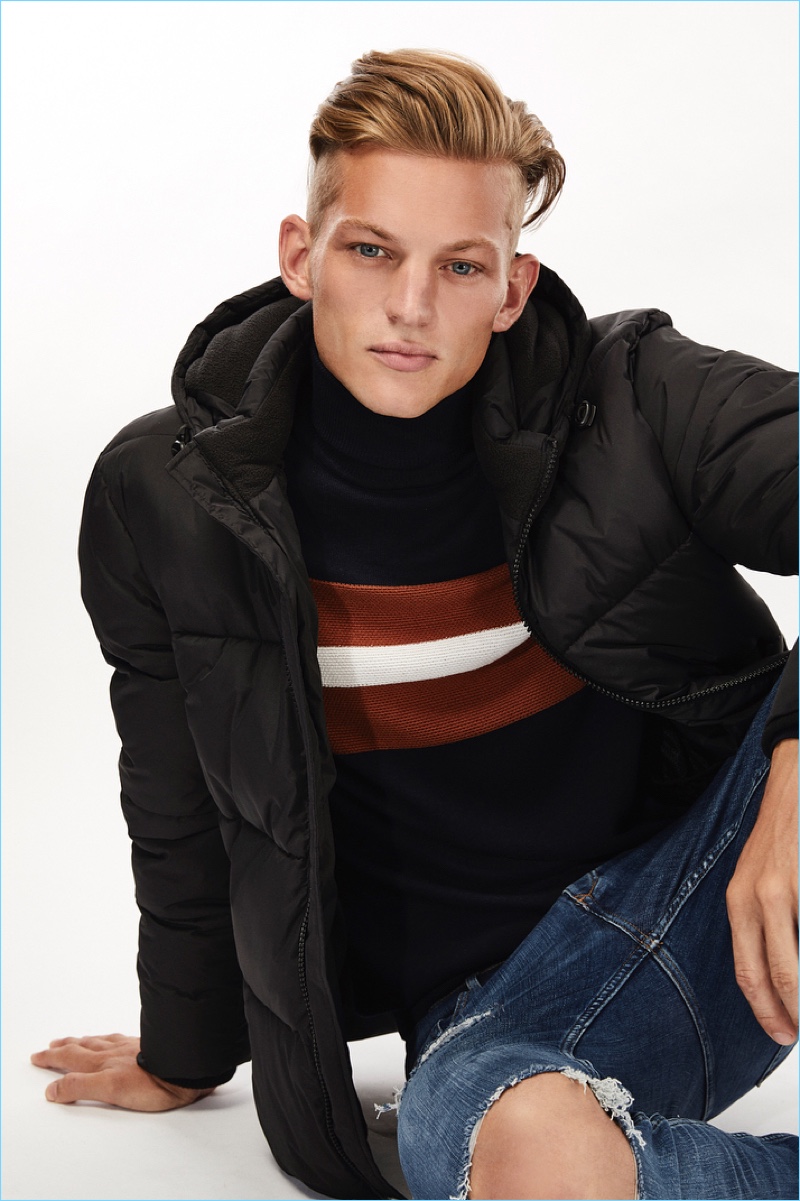 Sebastian Sauvè dons a River Island turtleneck sweater. He also sports a puffer jacket and ripped jeans.
