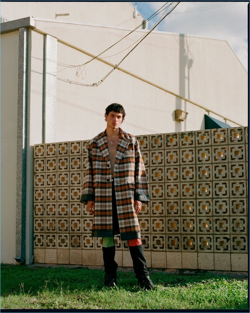 Front and center, Luka Isaac wears a Prada check coat, Raf Simons jeans, and ROA sneakers.