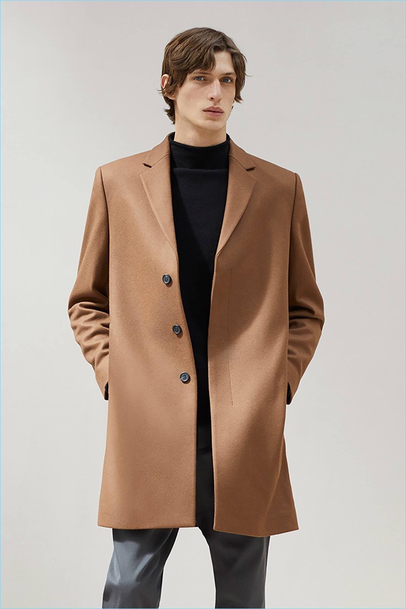 Edoardo Sebastianelli dons a brown coat and mock turtleneck sweater from COS.