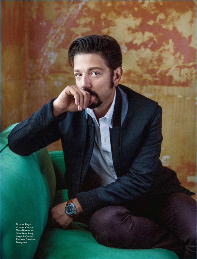 Sitting  for a photo, Diego Luna wears an Ermenegildo Zegna Couture jacket, Thom Browne shirt, Jaeger-LeCoultre watch, and Salvatore Ferragamo trousers.