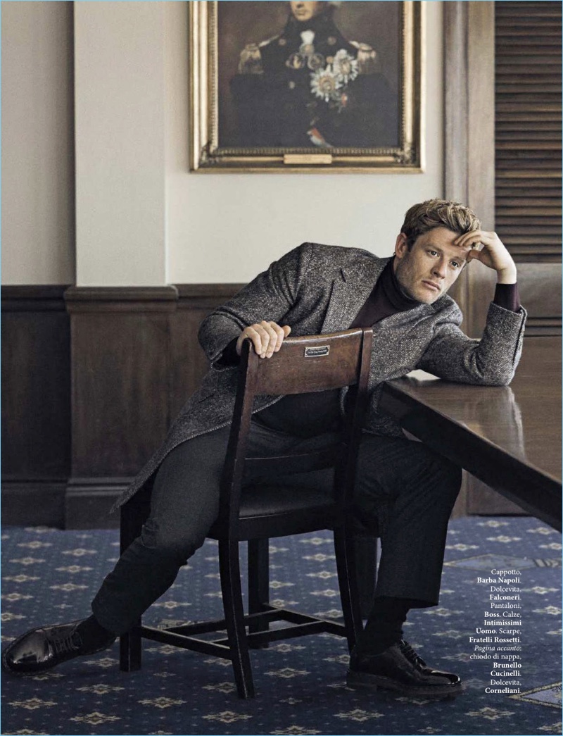 Sitting for a photo, James Norton sports a Barba Napoli coat, Falconeri turtleneck, BOSS trousers, and Fratelli Rossetti shoes.