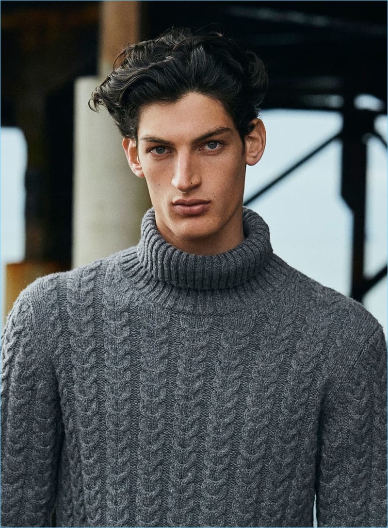 Aaron Shandel models a cable-knit turtleneck sweater in grey from Massimo Dutti.