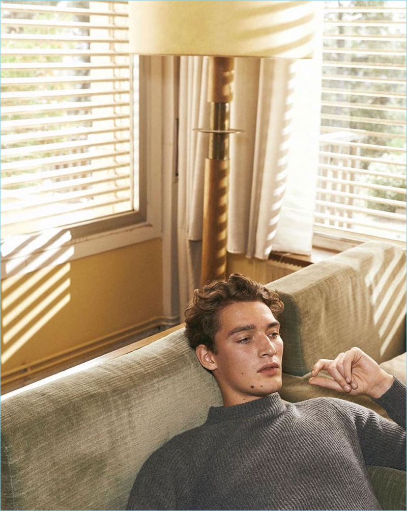 Relaxing, Otto Lotz wears a ribbed mock-neck sweater from Massimo Dutti.