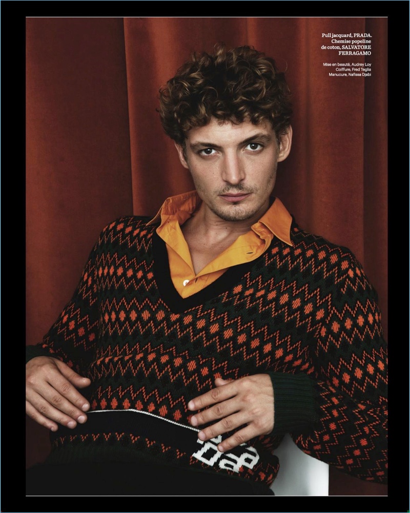 Starring in a photo shoot, Niels Schneider wears a Prada sweater with a shirt and pants from Salvatore Ferragamo.