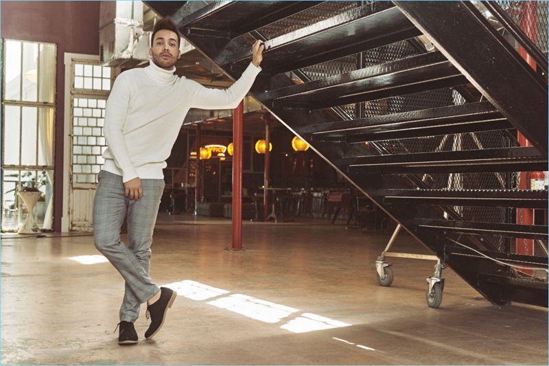 Prince Royce wears a white rib-knit turtleneck sweater, houndstooth suit pants, and leather derby shoes from H&M.