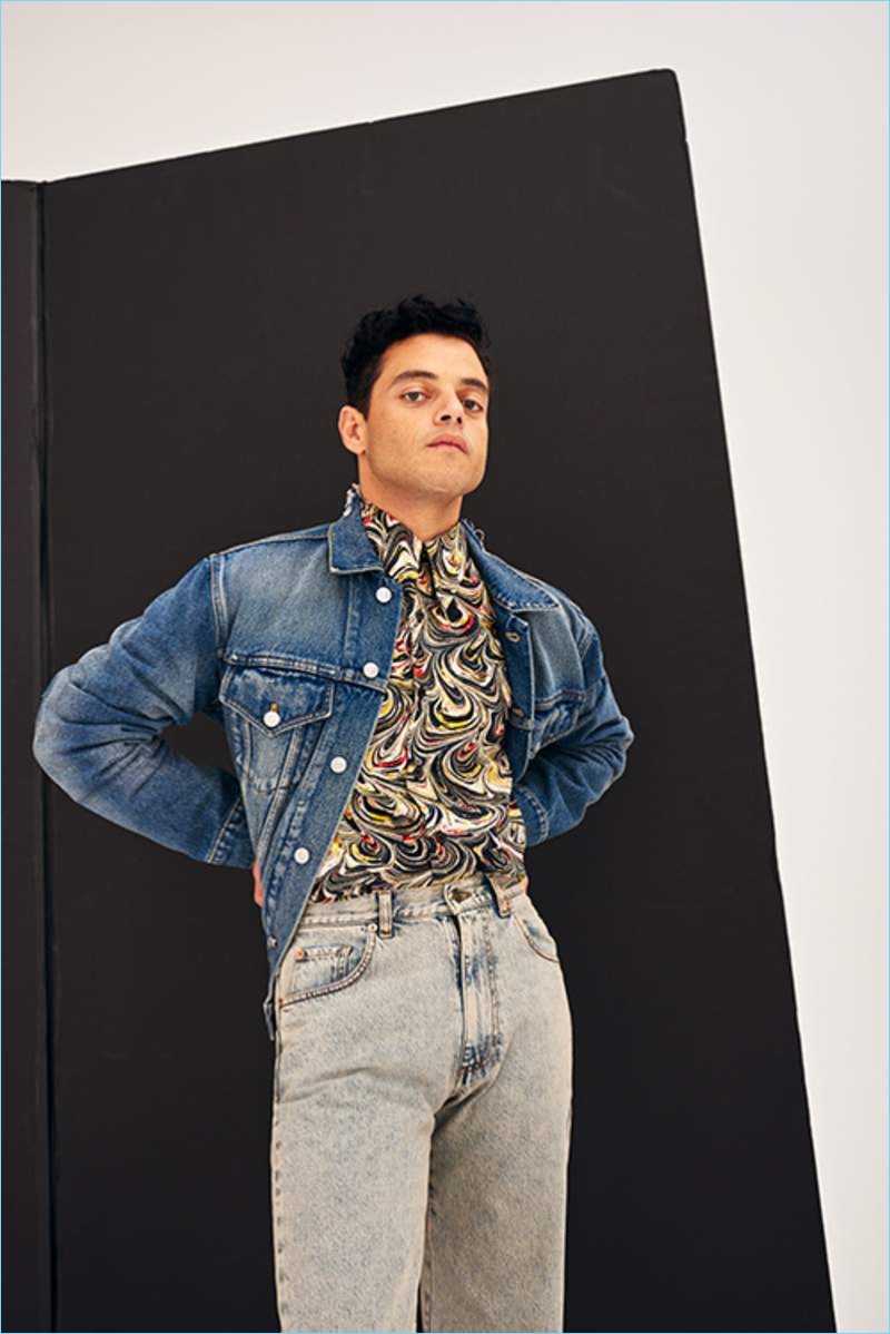 Going casual, Rami Malek wears a Balenciaga denim jacket, Dries Van Noten shirt, and Gucci jeans.