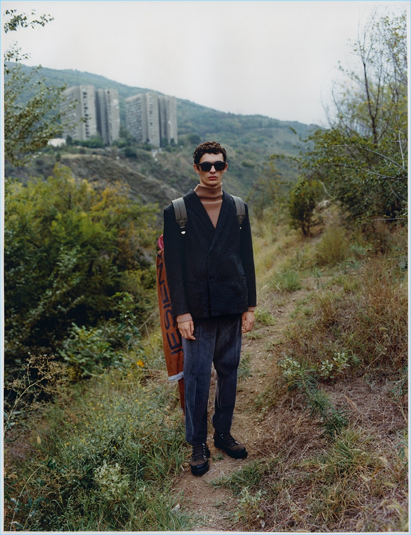 Model Piero Méndez dons a tweed wool-blend blazer and turtleneck with sunglasses and a backpack from Reserved's Re.Design.03 collection.