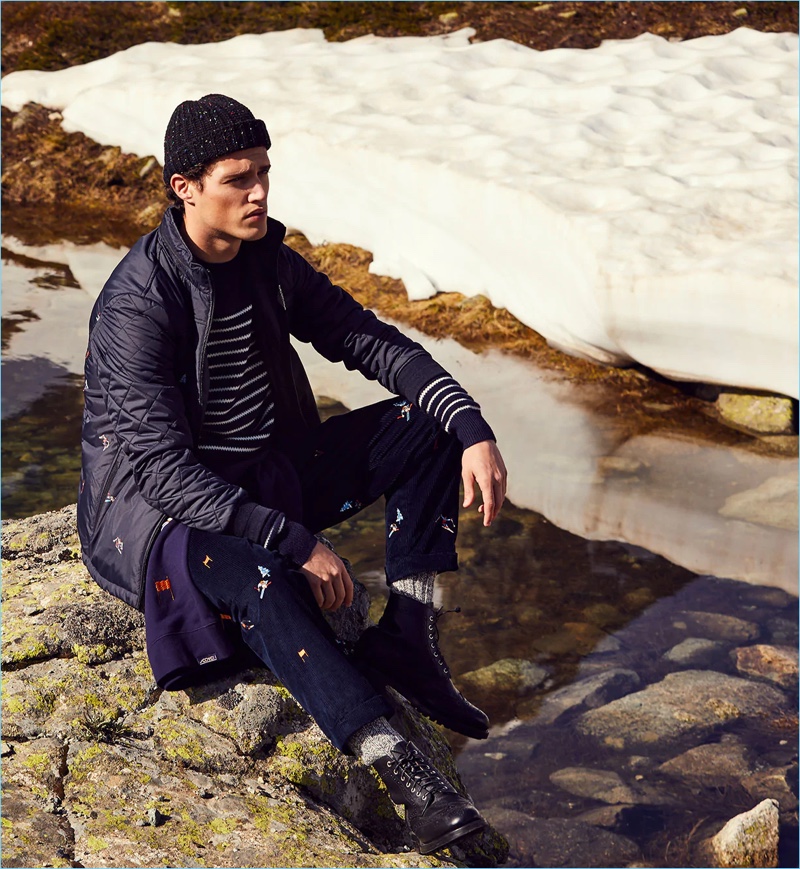 Connecting with Scotch & Soda for fall-winter 2018, Benjamin Reynier wears an embroidered jacket, striped sweater, ski artwork corduroy pants, and a chunky beanie.