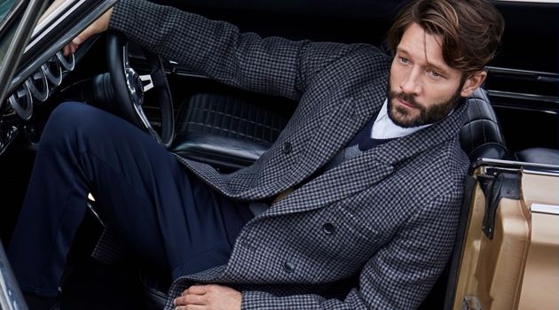 John Halls Sports Fall '18 Outerwear for Simons Relaxing in a vintage car, John Halls dons a LE 31 check overcoat, argyle sweater, officer collar shirt, , and piqué-stripe athletic pants.