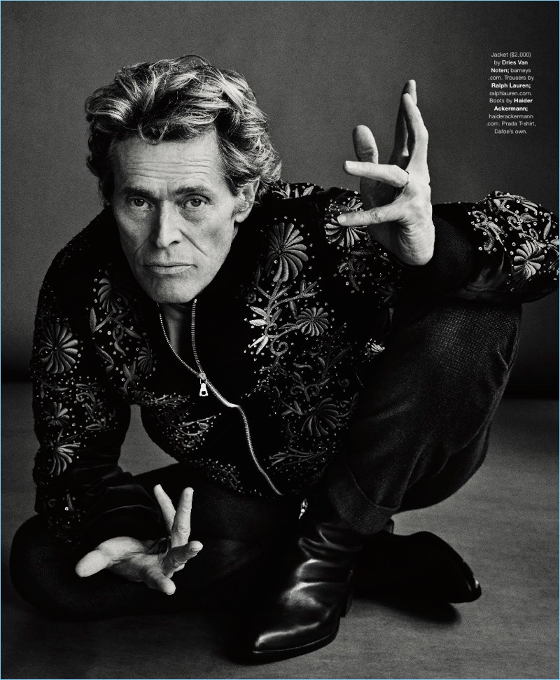 Starring in a photo shoot, Willem Dafoe sports a Dries Van Noten jacket, Ralph Lauren trousers, Haider Ackermann boots, and a Prada t-shirt.