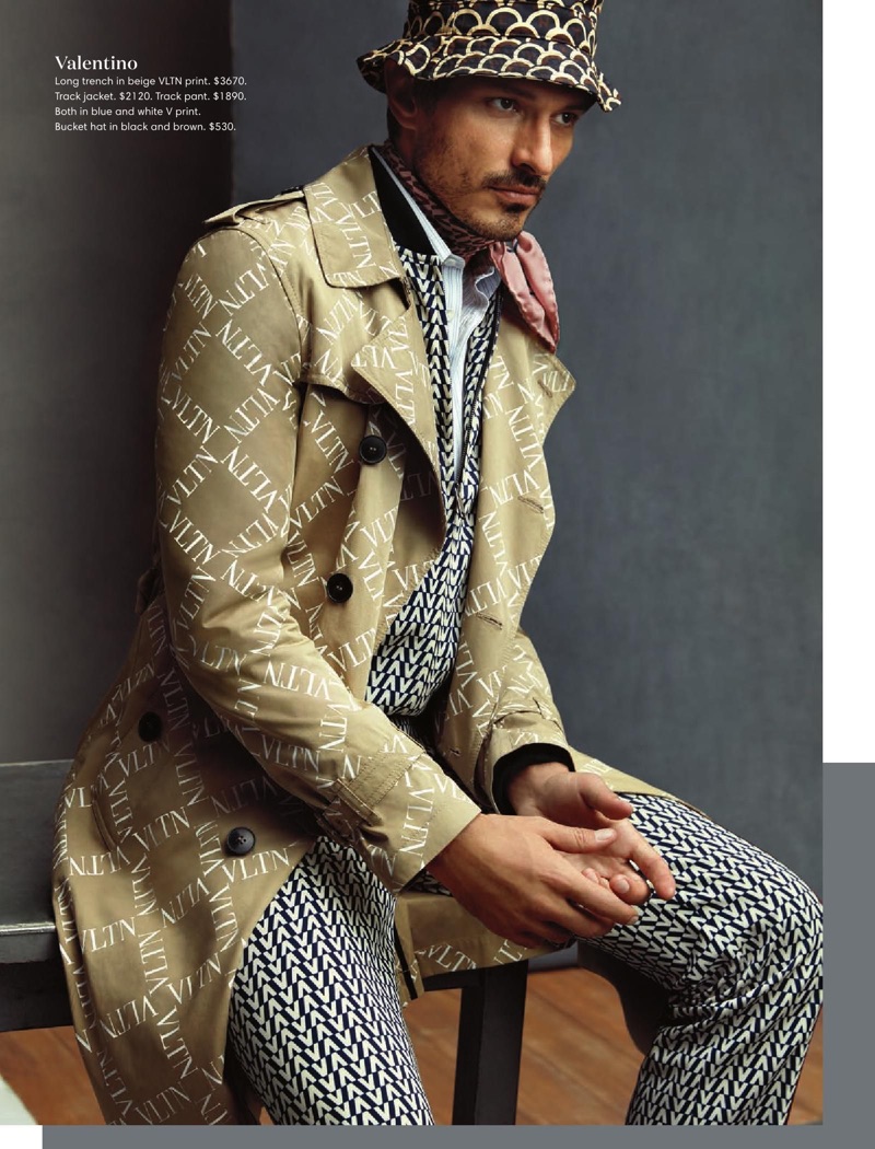 Making a printed statement, Andres Velencoso wears a Valentino logo print trench coat, track suit, and bucket hat.