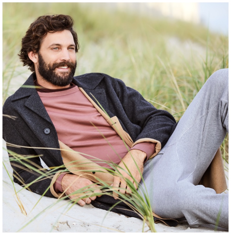 All smiles, David Enrico wears a Rag & Bone stripe tee, Save Khaki sweatshirt, Theory coat, and Rag & Bone Standard sweatpants.