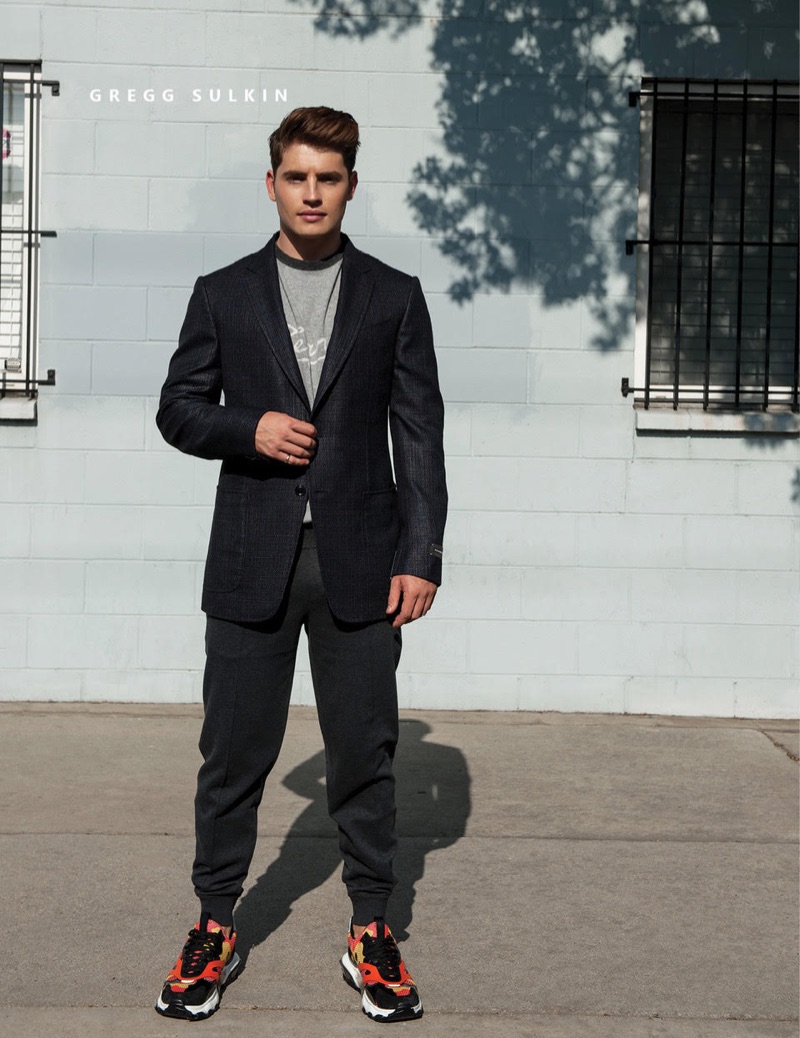 Gregg Sulkin rocks an Ermenegildo Zegna suit jacket and sweater with Brunello Cucinelli pants and Valentino sneakers.