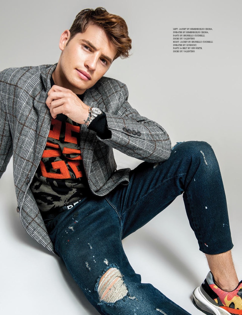 Taking to the studio, Gregg Sulkin sports a Brunello Cucinelli suit jacket, Givenchy sweater, and Valentino sneakers with a belt and jeans by Off-White.