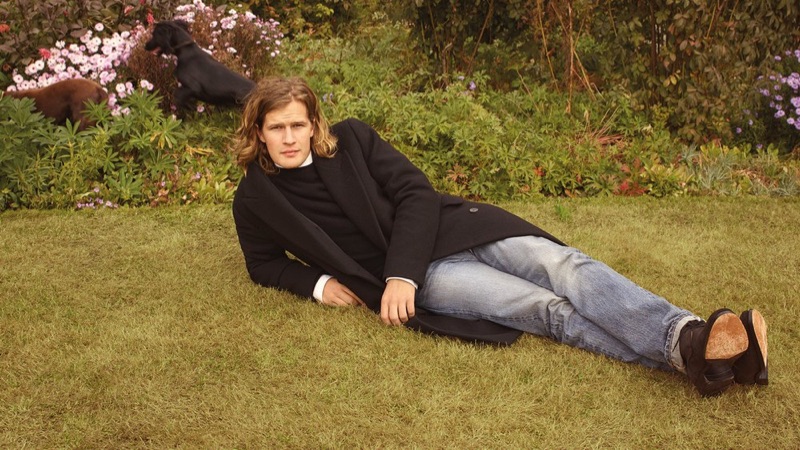 Relaxing, Lord March wears a double-breasted cashmere coat, shirt, slim-fit cashmere sweater, and selvedge denim jeans from The Row.