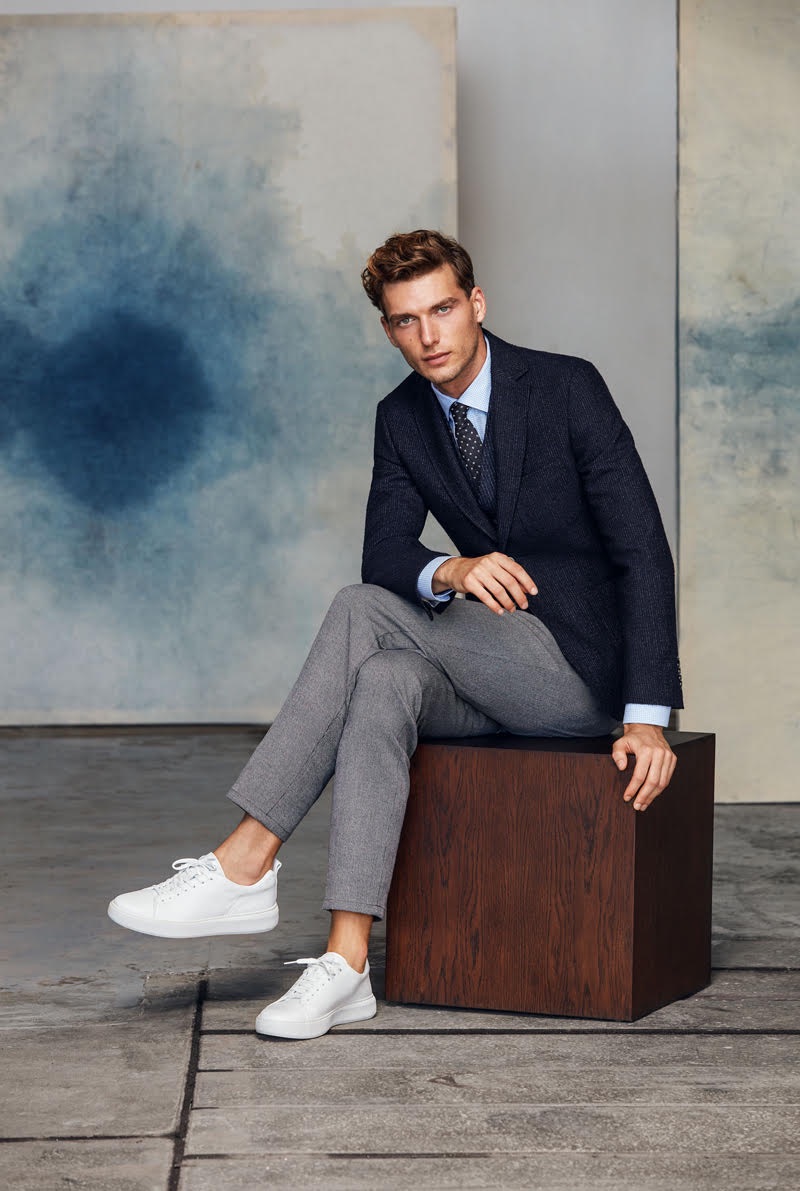 Sitting for a portrait, Nikola Jovanovic wears tailored garments by Lufian with white sneakers.