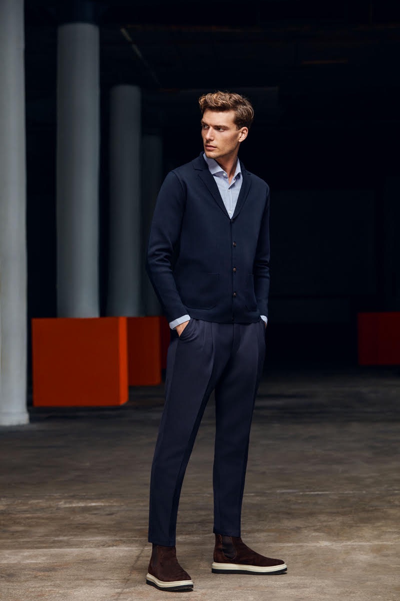 Standing tall, Nikola Jovanovic models a cardigan sweater, oxford, and trousers by Lufian.