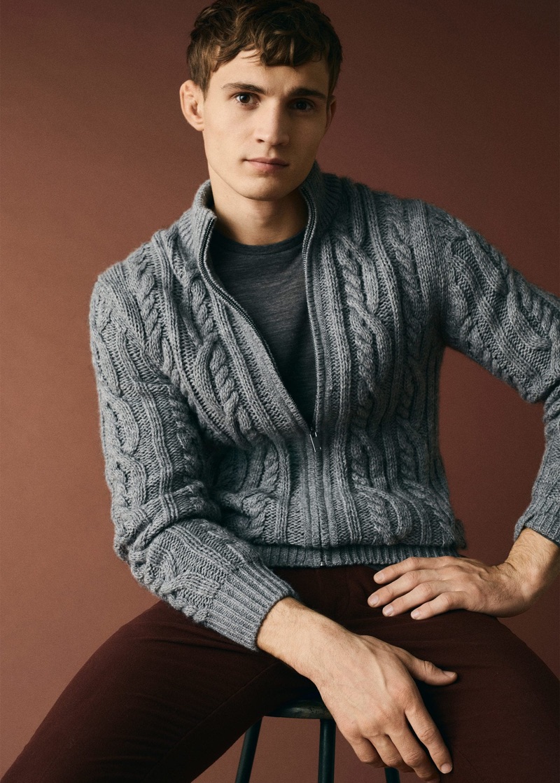 Sitting for a portrait, Julian Schneyder wears a zippered cable-knit sweater from Mango Man.