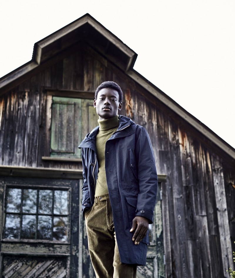 Embracing fall tones, Youssouf Bamba wears a Todd Snyder olive green cashmere turtleneck sweater and green corduroy trousers. A navy Todd Snyder parka completes Youssouf's look.