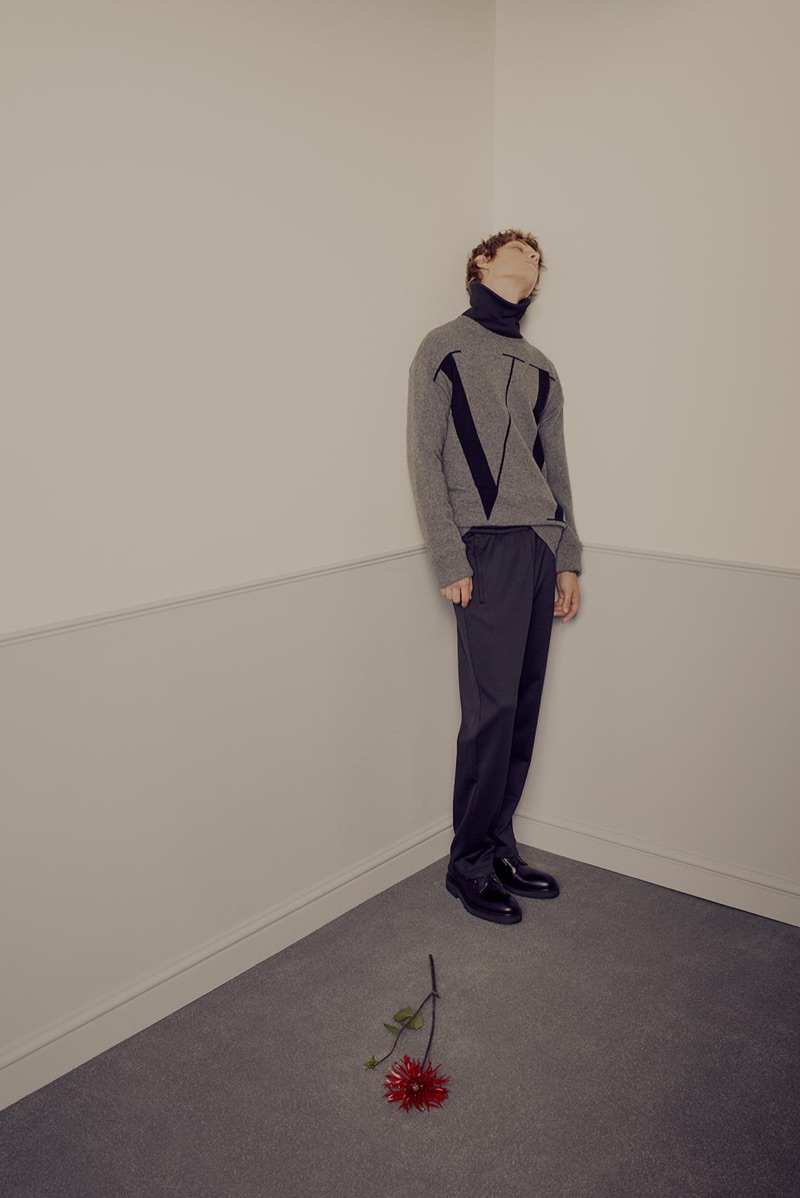 Directed to the corner, Serge Sergeev wears a Valentino sweater, logo-print turtleneck sweater, track pants, and leather desert boots.