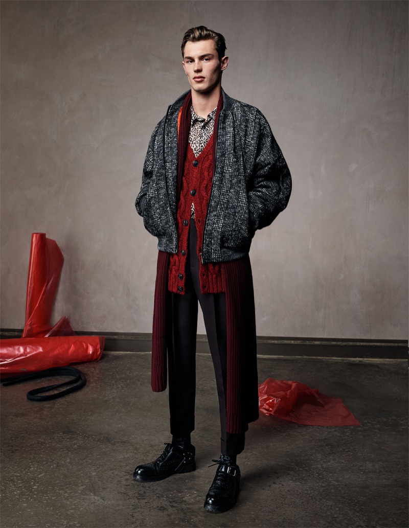 Kit Butler sports a houndstooth bomber jacket with a red cable-knit cardigan sweater, slim-fit trousers, and a leopard shirt by Zara Man.