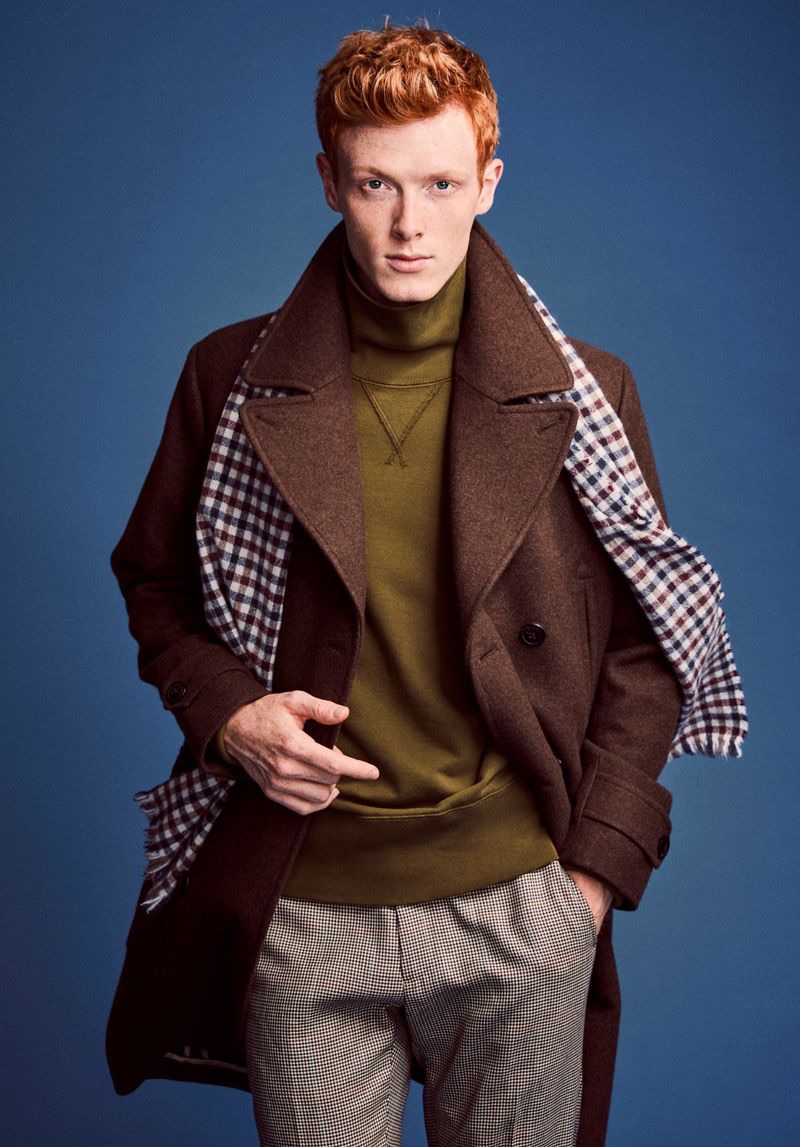 Linus Wordemann dons a Todd Snyder officer coat in brown with Made in New York houndstooth pleated trousers. He also wears a Todd Snyder + Champion turtleneck sweatshirt.