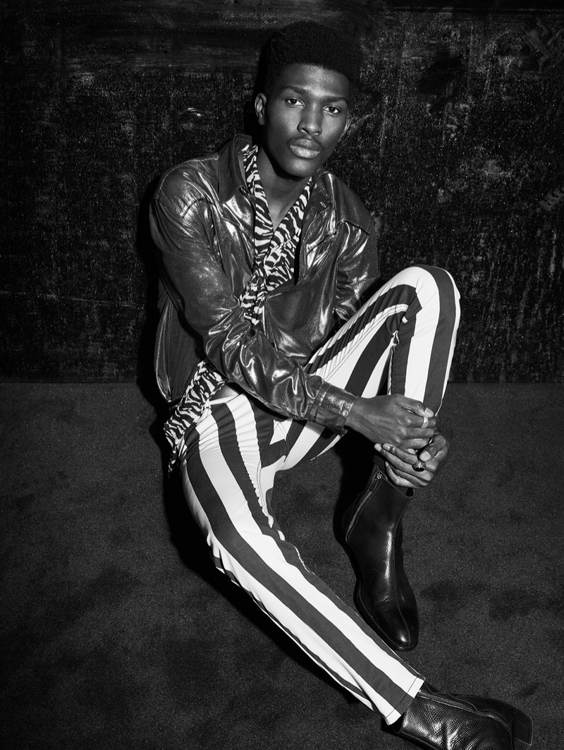 Embracing rock 'n' roll party style, Anarcius Jean wears a glittery jacket with a zebra print shirt, striped pants, and boots.