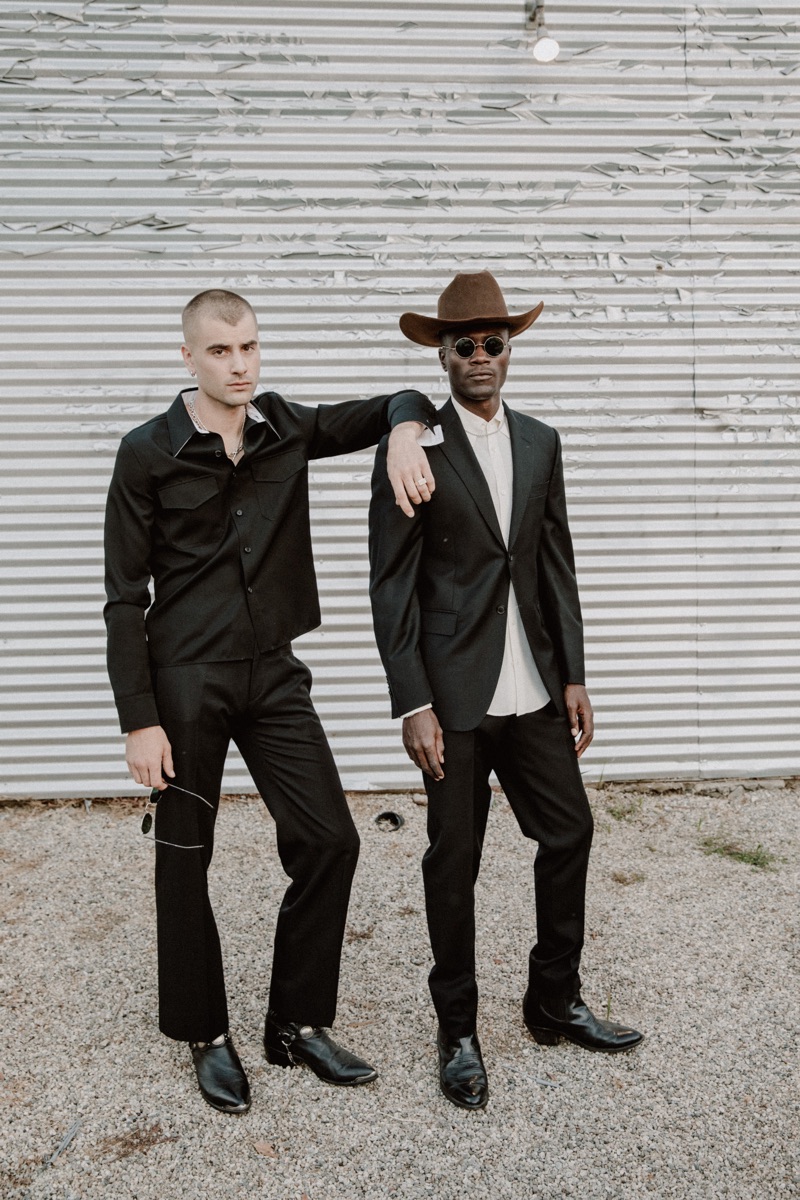 Left to Right: Blake wears shirt Calvin Klein, trousers Yves Saint Laurent, and vintage cowboy boots. Remi wears cowboy hat Stetson, suit Balmain, vintage French shirt and cowboy boots.
