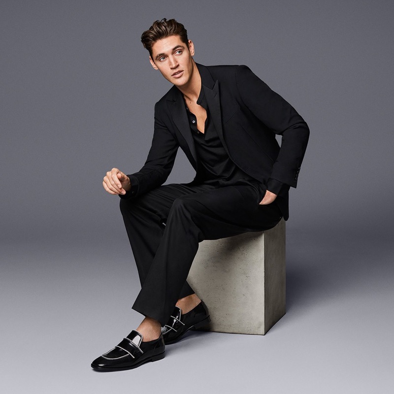 Isaac Carew dons Jimmy Choo's black shiny calf loafers with white rope binding.