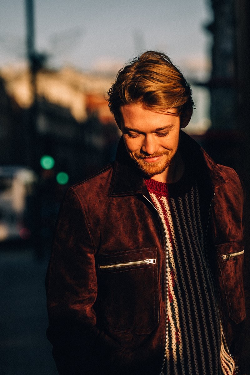 All smiles, Joe Alwyn wears a Tom Ford suede blouson jacket and Saint Laurent striped sweater.