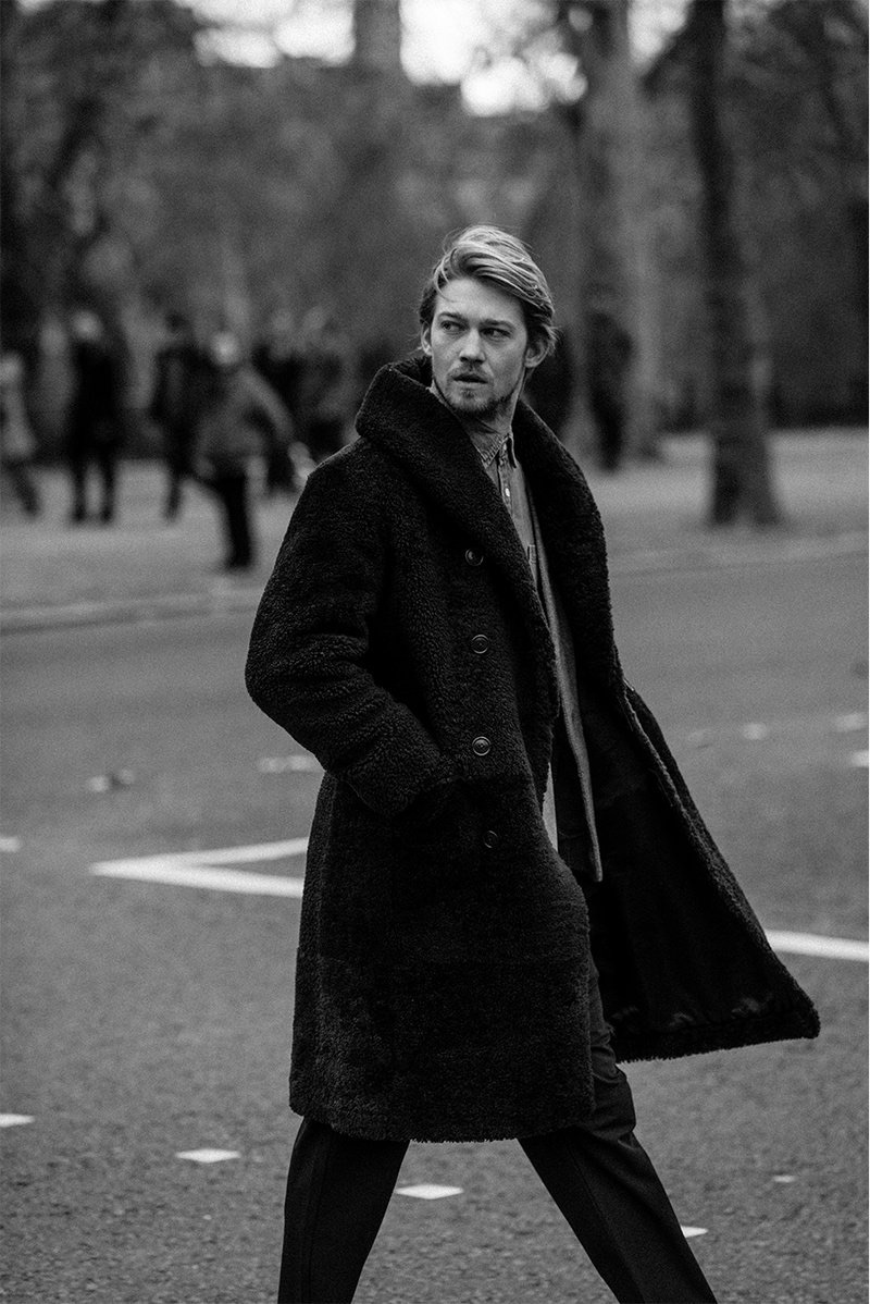 Out for a stroll, Joe Alwyn wears a RRL shearling coat, Visvim wool cardigan, Frame chambray shirt, and Barena trousers. 