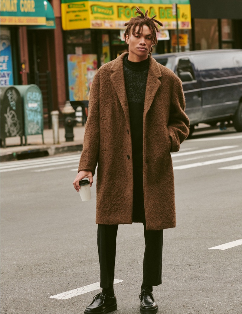 Seth Hill dons a Ted Baker sweater, Lemaire coat, Stüssy cropped trousers, Theory mock tee, and Saturdays NYC shoes.