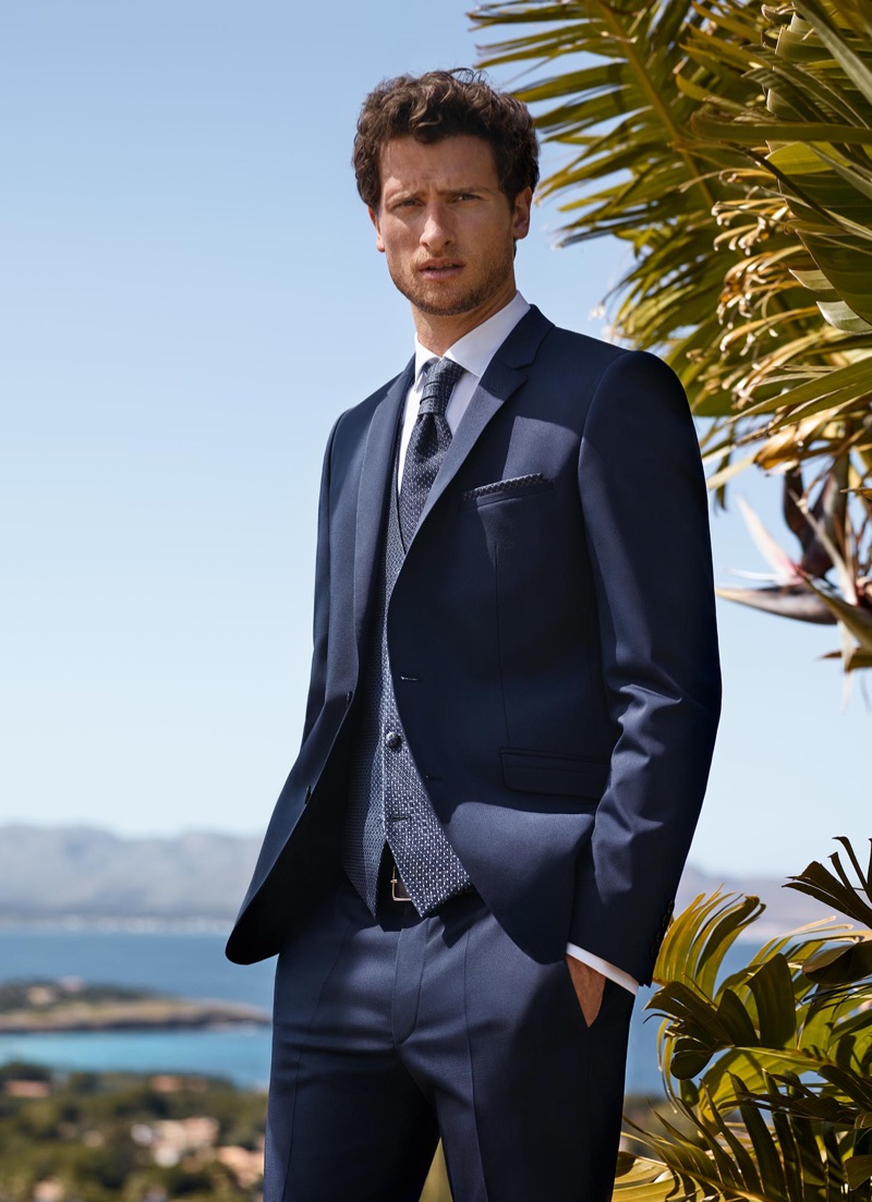 Embracing navy, Tom Warren wears a three-piece suit by Digel Ceremony.