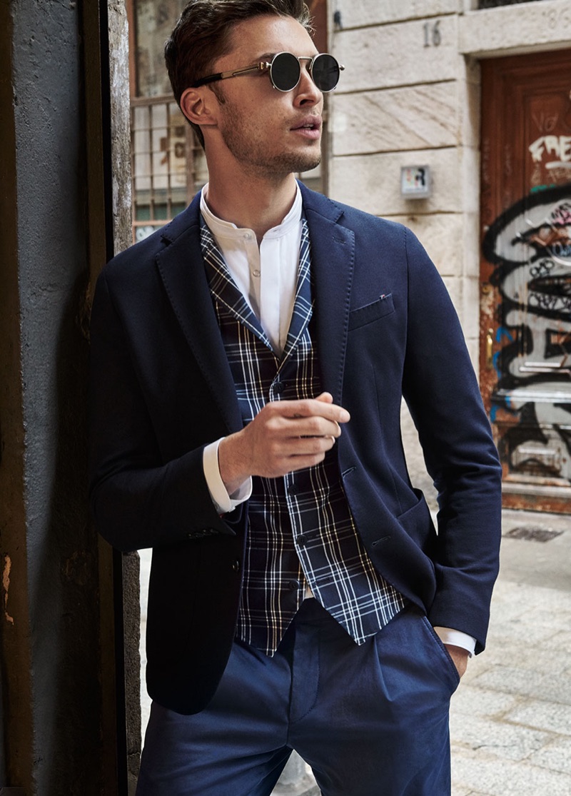 British model Harvey Haydon dons a navy blazer, check waistcoat, and pleated pants from Digel Move.