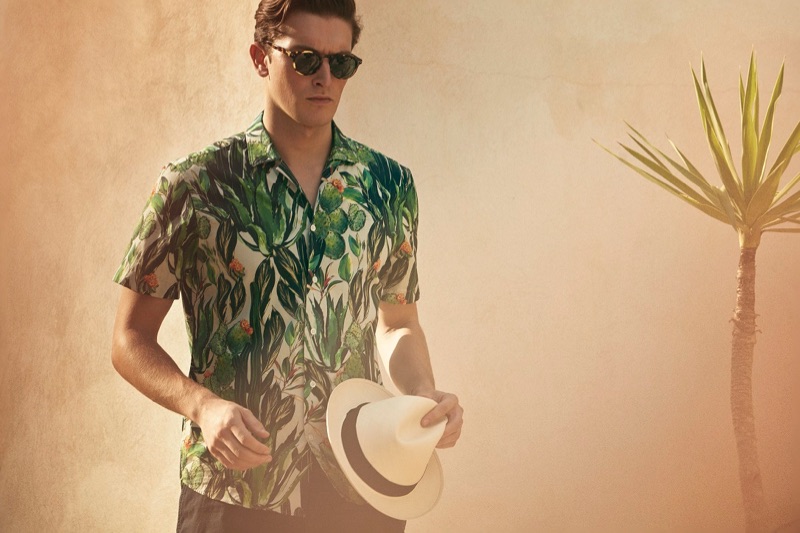 Embracing a tropical vibe, Oli Lacey sports a short-sleeve printed shirt for Gieves & Hawkes' spring-summer 2019 campaign.